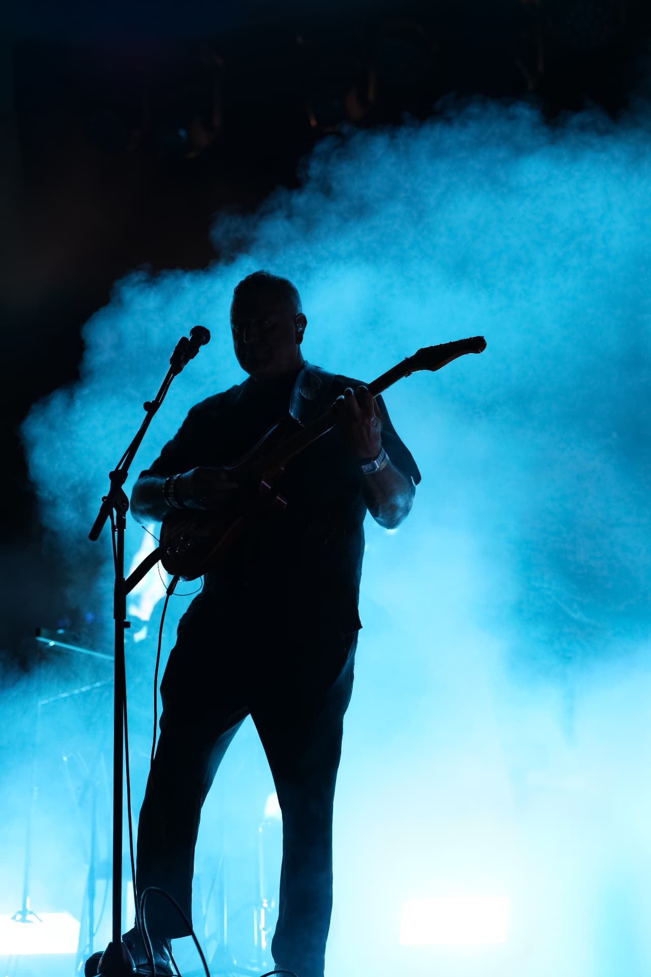 Moshe Peretz — guitarist silhouetted against blue smoke