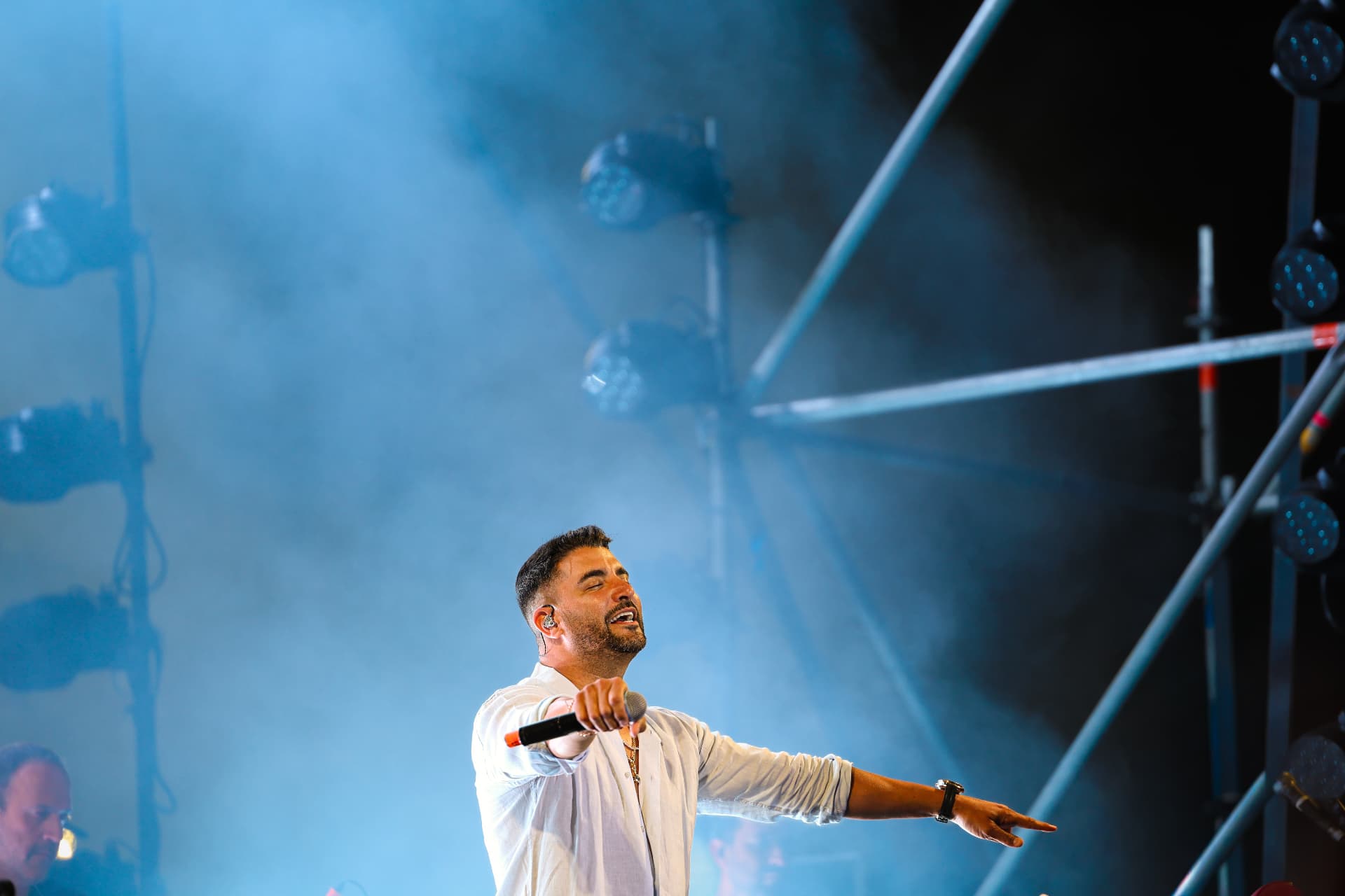 Moshe Peretz performing beneath blue stage light